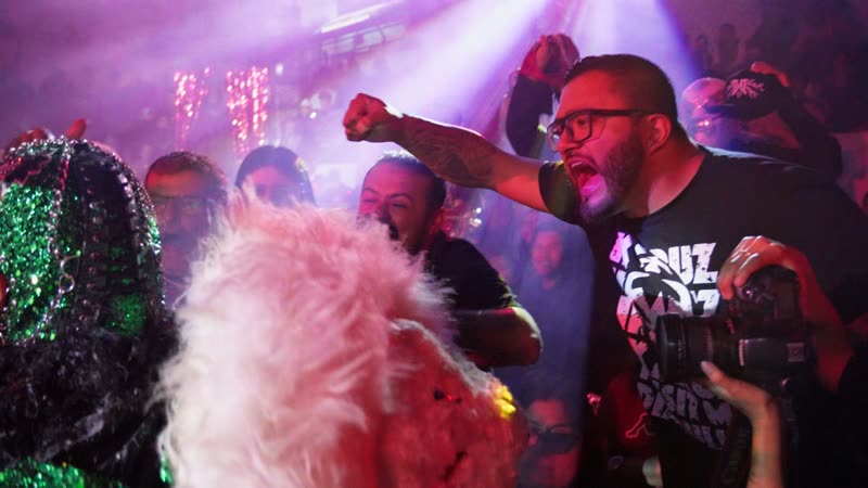 Fans celebrando junto a luchadores enmascarados en función de lucha libre en Arena Qro Querétaro con iluminación profesional